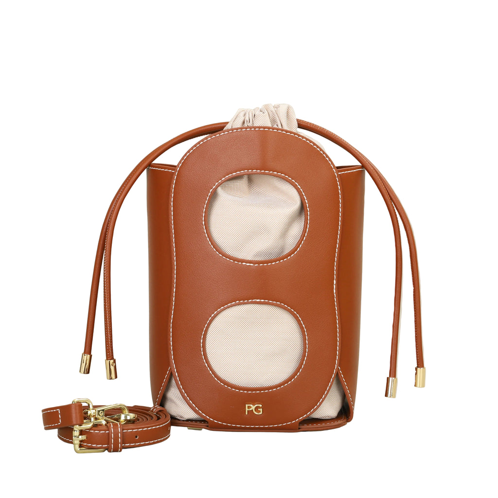 Brown leather bag with drawstring and strap on a beige background