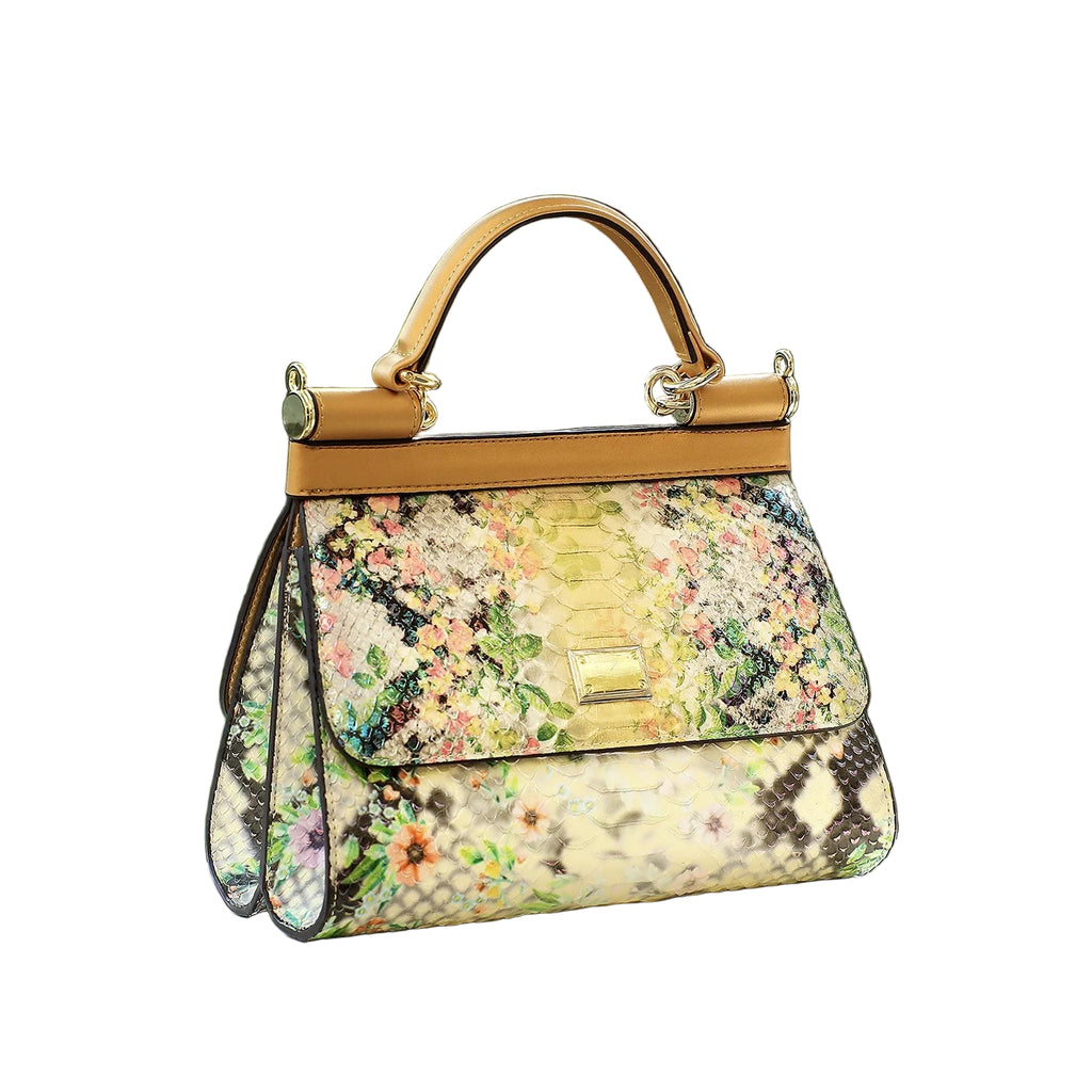 Floral patterned handbag with gold accents on a white surface with a green leafy background