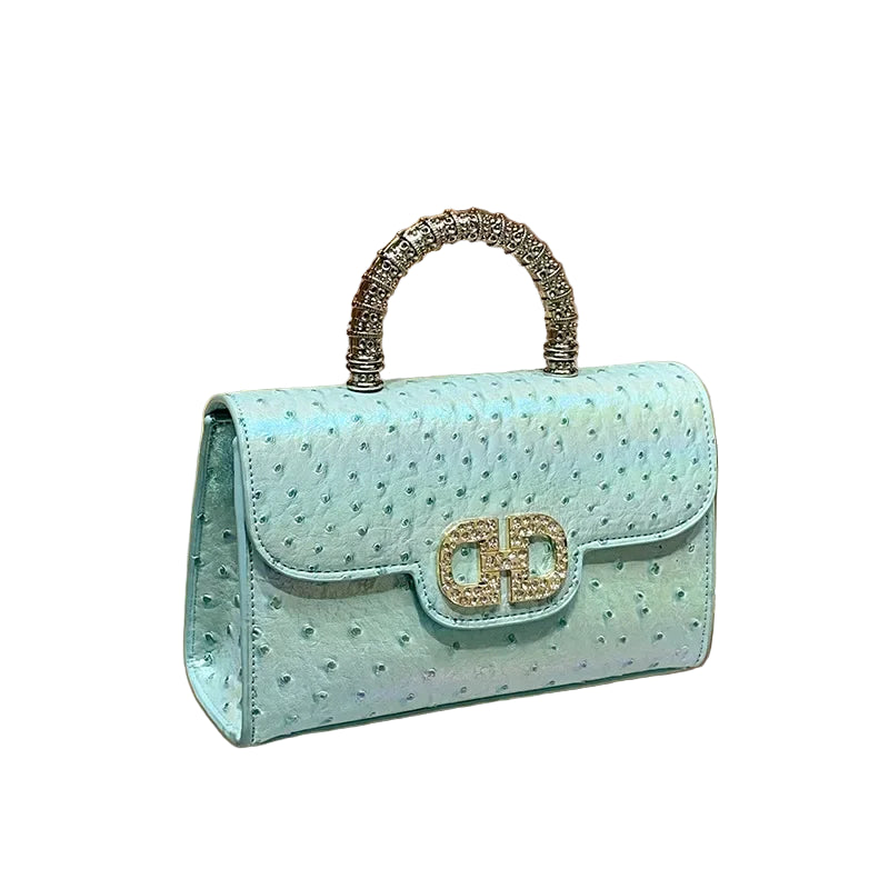 Light blue handbag with decorative handle on a wooden surface 