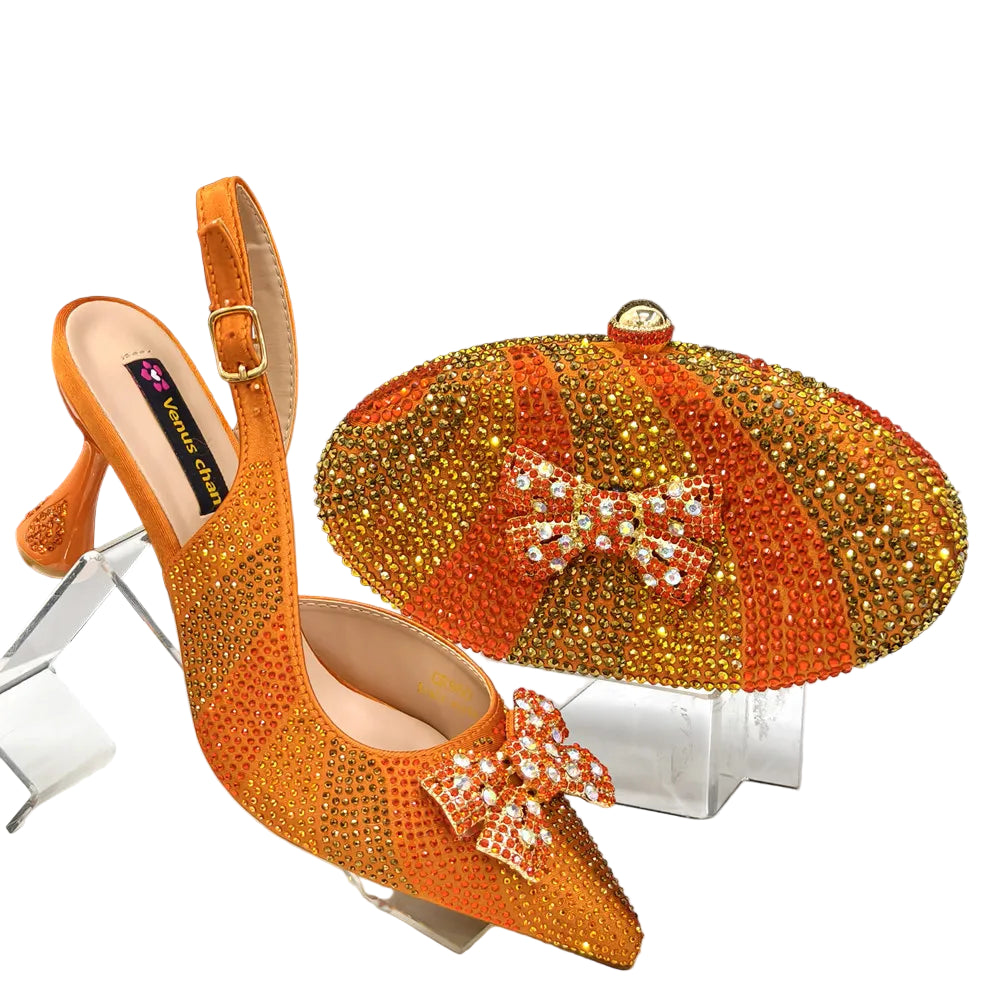 Orange high-heeled shoes with crystal embellishments and a matching clutch bag on a clear stand